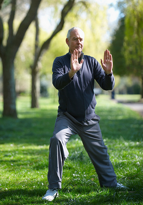 older man doing yoga outside